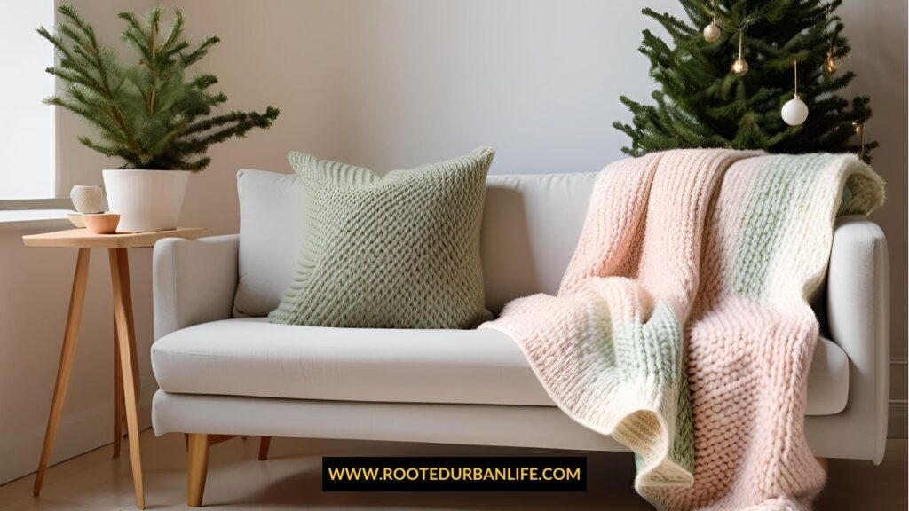 A hand-knit throw blanket draped over a sofa with neutral tones, Christmas lights twinkling softly in the background.