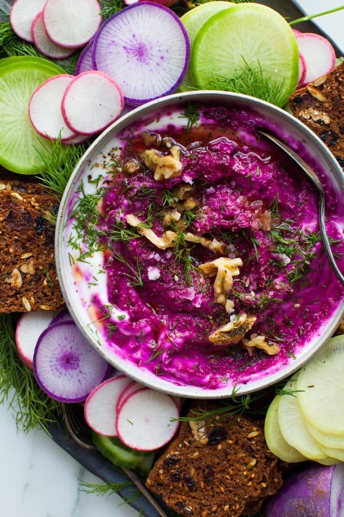 RoastedBeetWalnutDip Roasted beets dip in a bowl with veggies and crackers for dipping